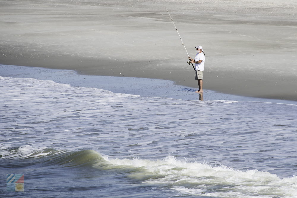 A man surf fishes on the beach
