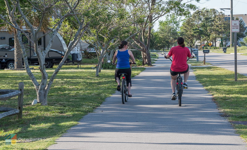 Two women ride bikes on a multi-use path