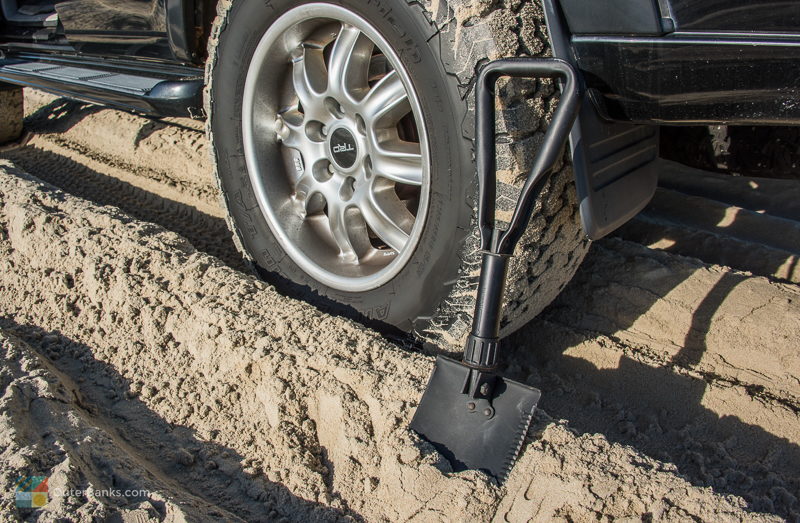 A shovel next to a 4x4 vehicle on the beach