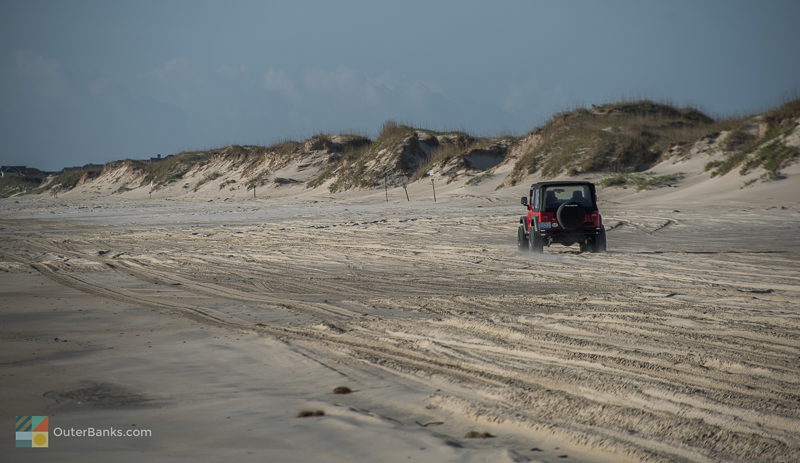 A 4x4 vehicle drives along the beach in Corolla NC