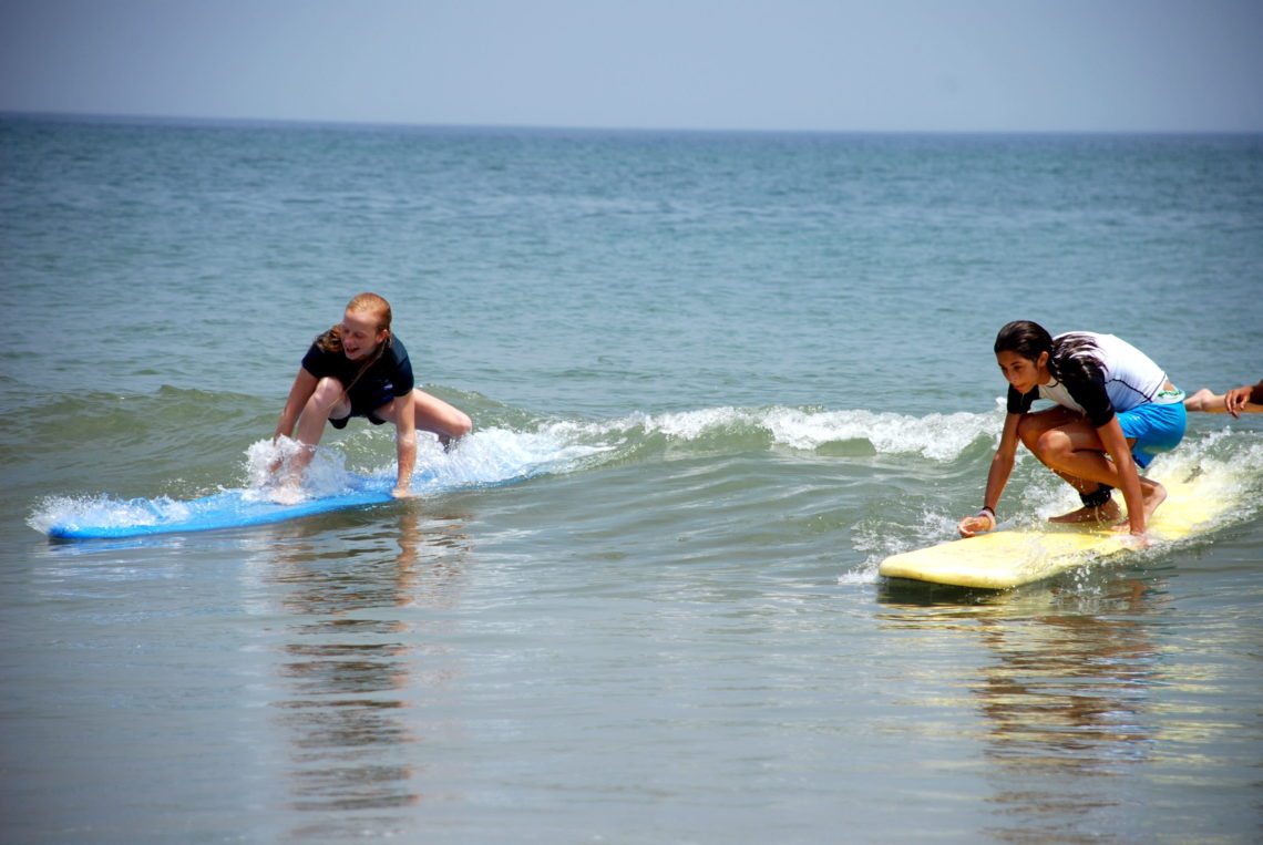 Two surfers catching waves - Kitty Hawk Surf Co.